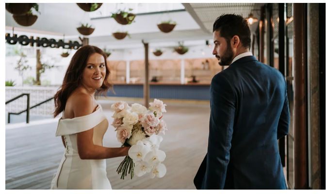A bride and groom are standing next to each other and the bride is holding a bouquet of flowers.