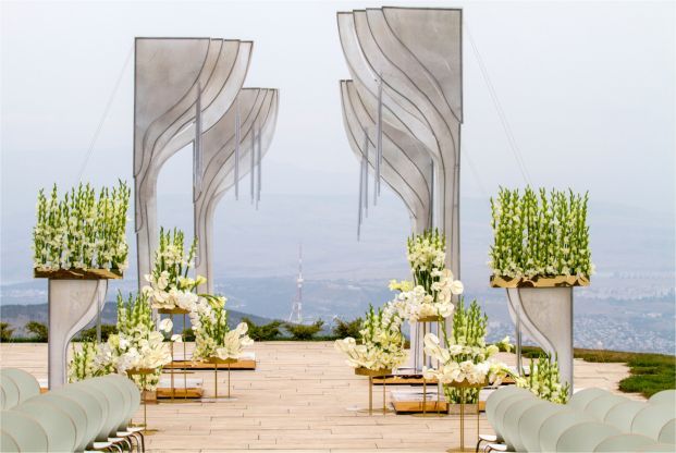 A wedding ceremony is taking place on a rooftop with a view of the ocean.