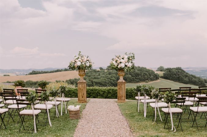 A row of chairs are lined up in a field for a wedding ceremony.