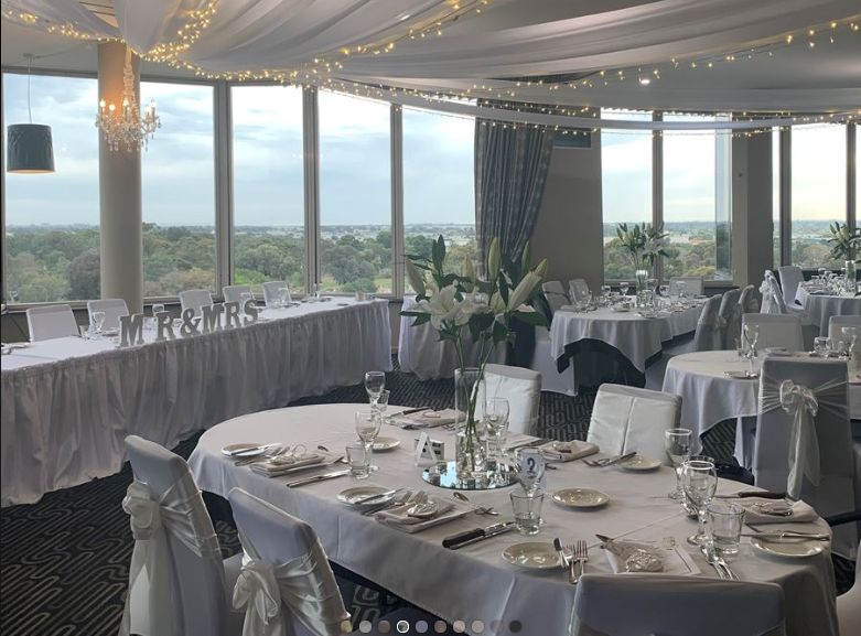 A large room with tables and chairs set up for a wedding reception.