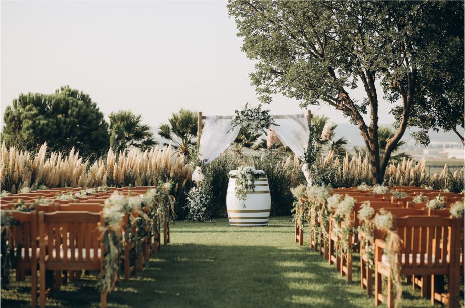 A row of wooden chairs are lined up in a field for a wedding ceremony.