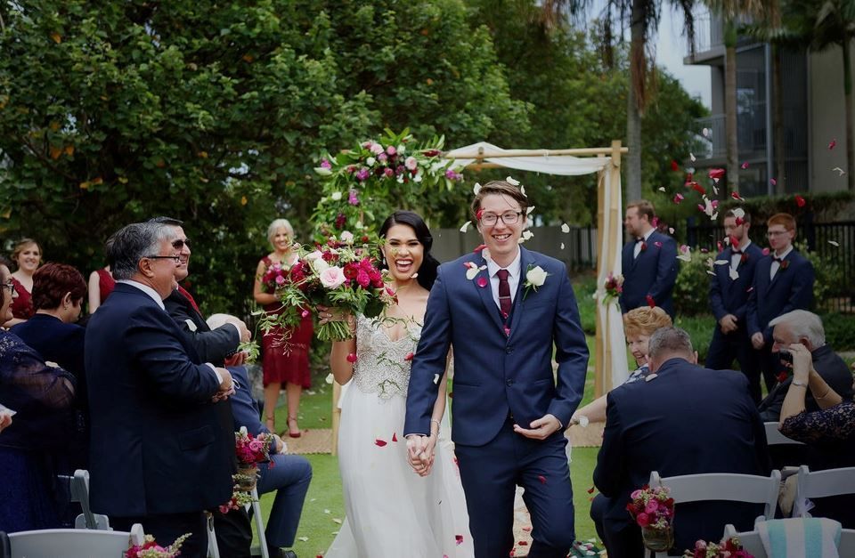 A bride and groom are walking down the aisle at their wedding holding hands.