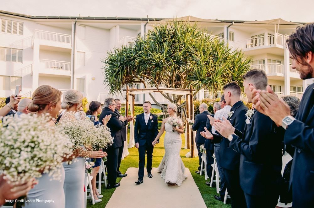 A bride and groom are walking down the aisle at a wedding ceremony.
