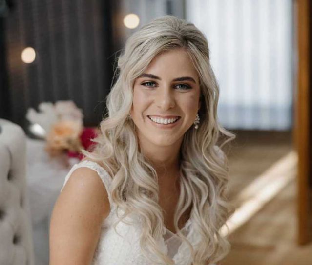 A woman in a white dress is smiling for the camera.