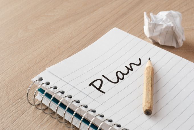 A spiral notebook with the word plan written on it