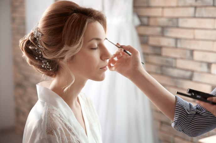 A woman is getting her makeup done by a makeup artist.