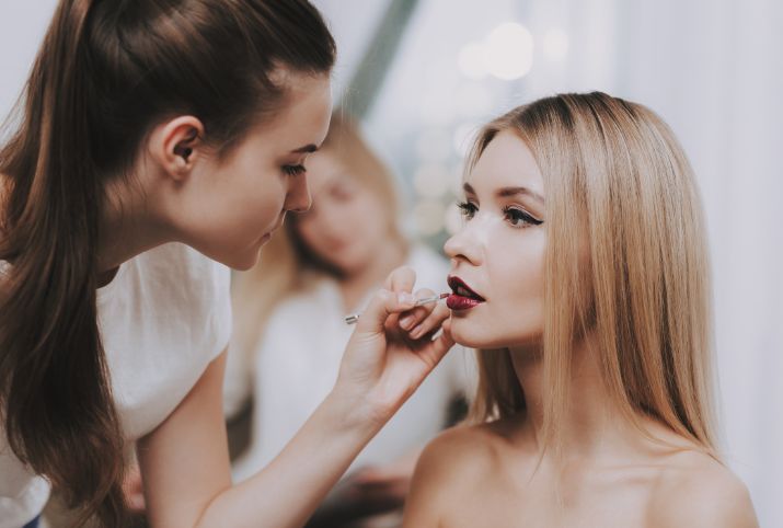 A woman is applying makeup to another woman 's face.