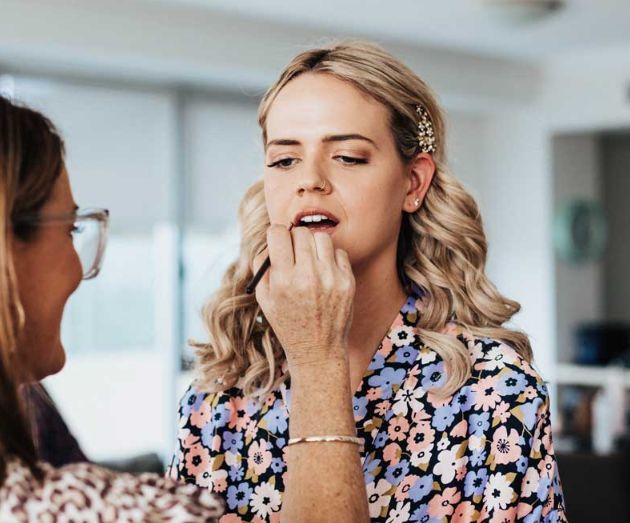 A woman is getting her makeup done by a makeup artist.