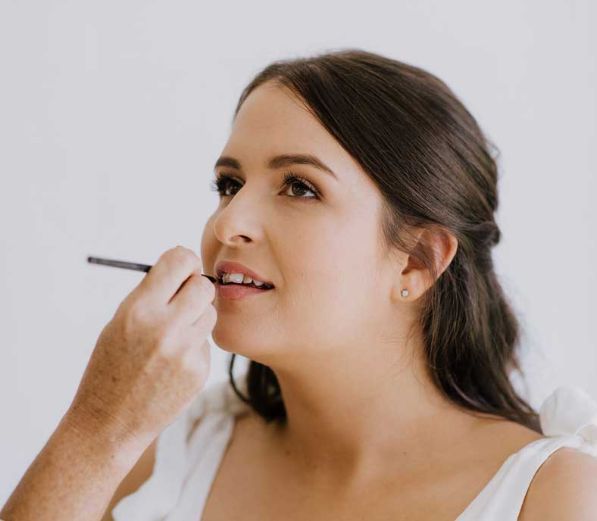 A woman is getting her makeup done by a makeup artist.