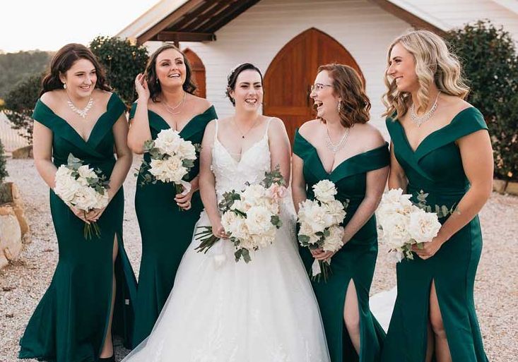 A bride and her bridesmaids are posing for a picture in front of a church.