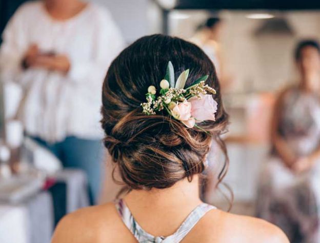 The back of a woman 's head with a bun and flowers in her hair.