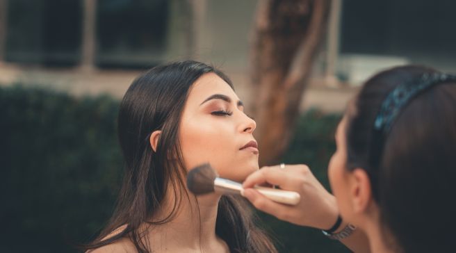 A woman is getting her makeup done by a makeup artist.