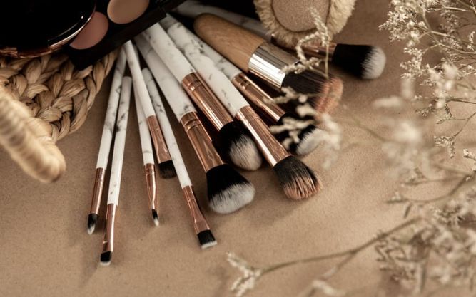 A bunch of makeup brushes are sitting on a table.