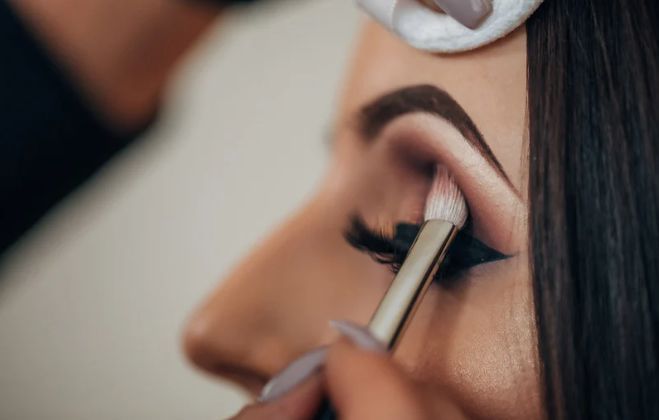 A woman is getting her eyebrows painted by a makeup artist.