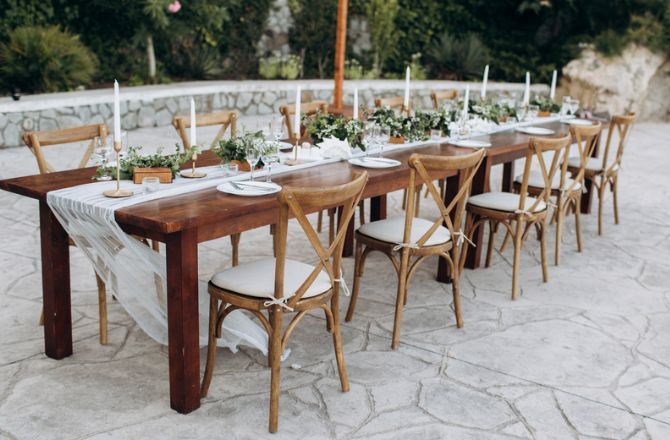 A long wooden table and chairs set up for a wedding reception.