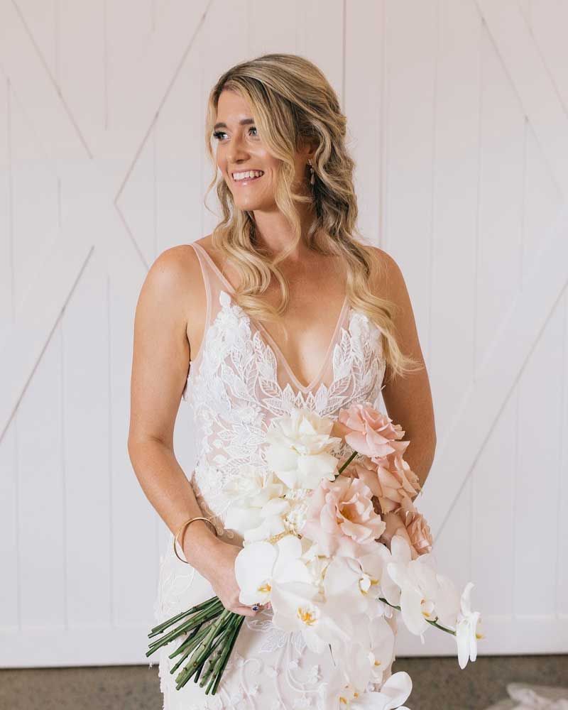 A bride in a white dress is holding a bouquet of flowers.