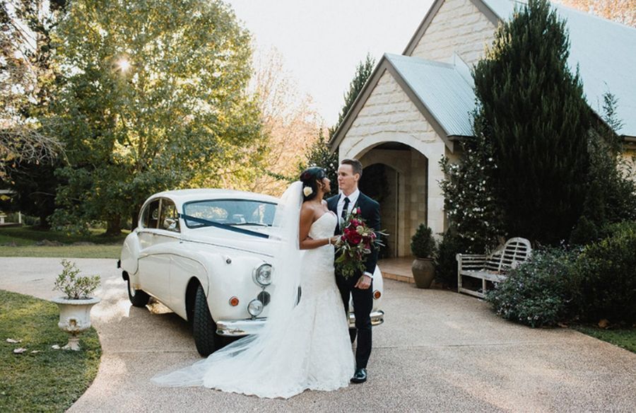 A bride and groom are kissing in front of a white van.