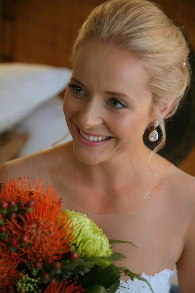 The bride is smiling and holding a bouquet of flowers.