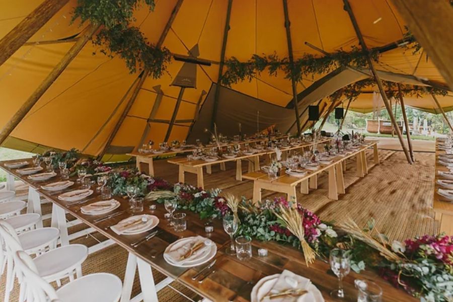 A large tent with a long table and chairs set up for a wedding reception.