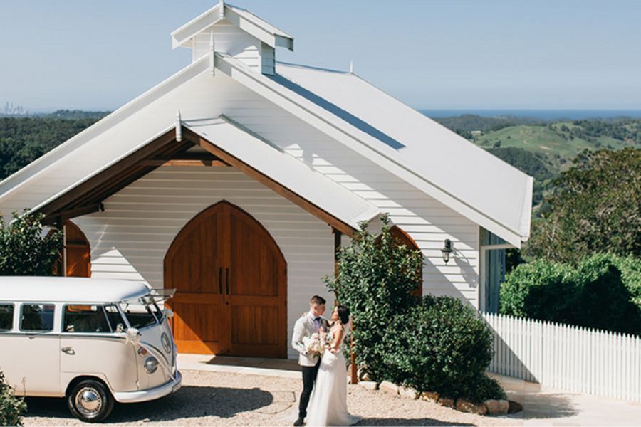 A bride and groom are kissing in front of a white van.