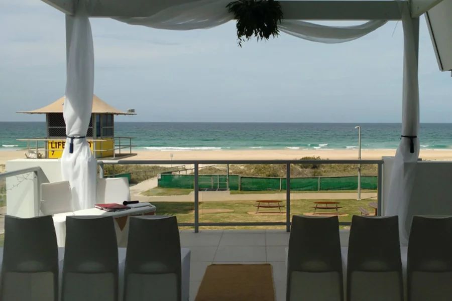 A lifeguard tower is visible from a balcony overlooking the ocean