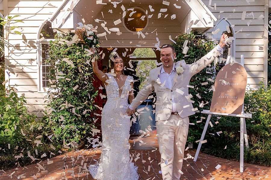 A bride and groom are kissing in front of a white van.
