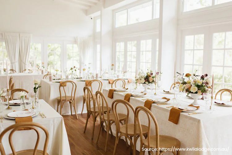 A room with tables and chairs set up for a wedding reception.