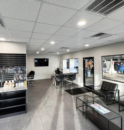 Modern salon interior with black chairs, mirrors, styling stations, and gray tile flooring | Dunedin Total Car Care