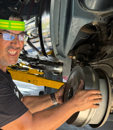 Mechanic working under a car, tightening a brake rotor in an auto shop | Dunedin Total Car Care