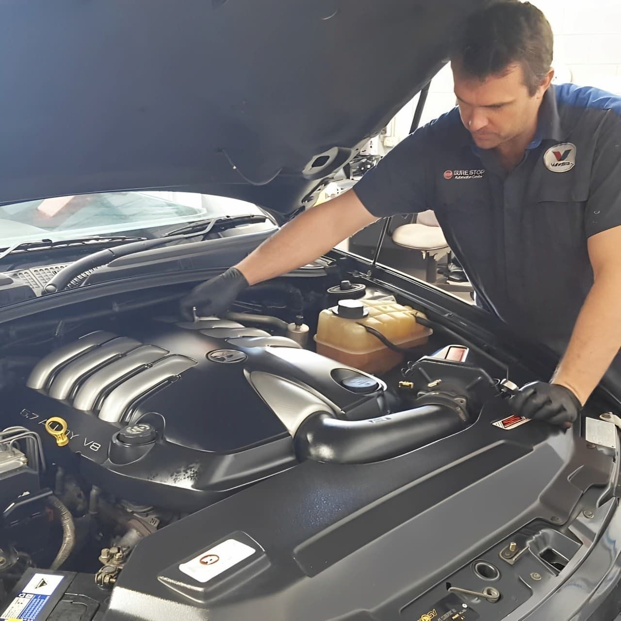A man is working on the engine of a car — Sure Stop Automotive Centre In Nerang, QLD