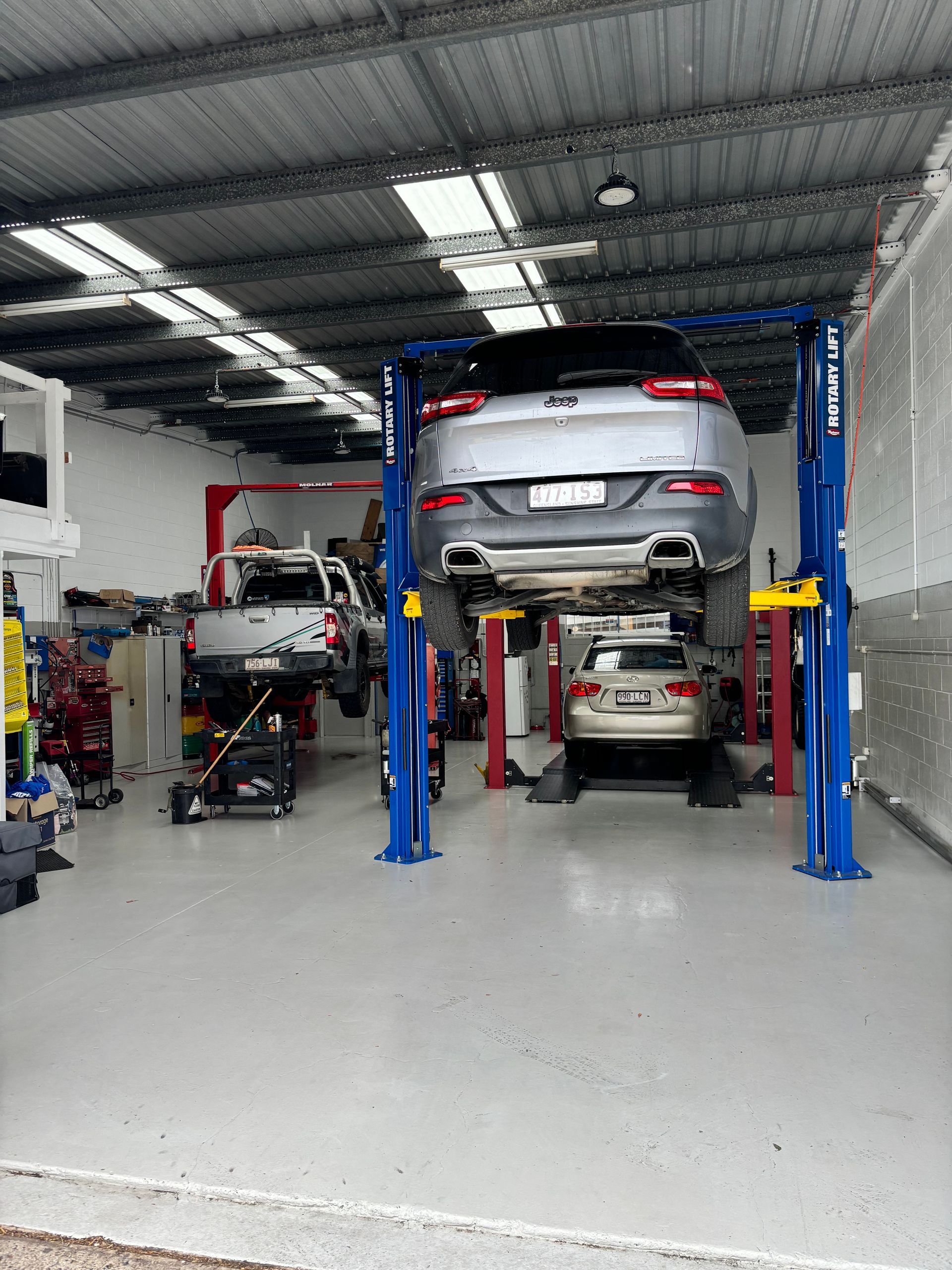 A car is sitting on a lift in a garage. — Sure Stop Automotive Centre In Nerang, QLD