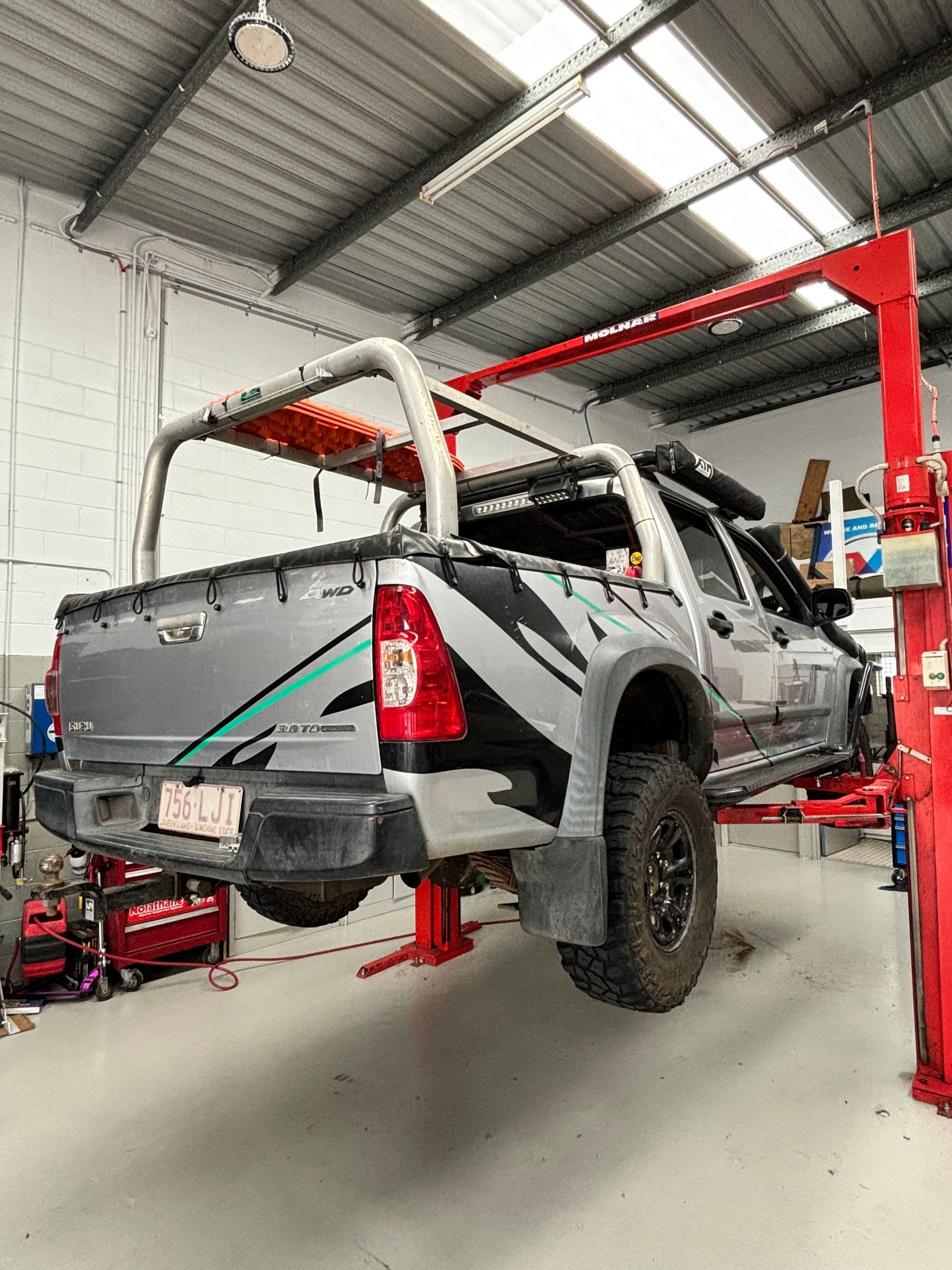 A truck is sitting on a lift in a garage. — Sure Stop Automotive Centre In Nerang, QLD