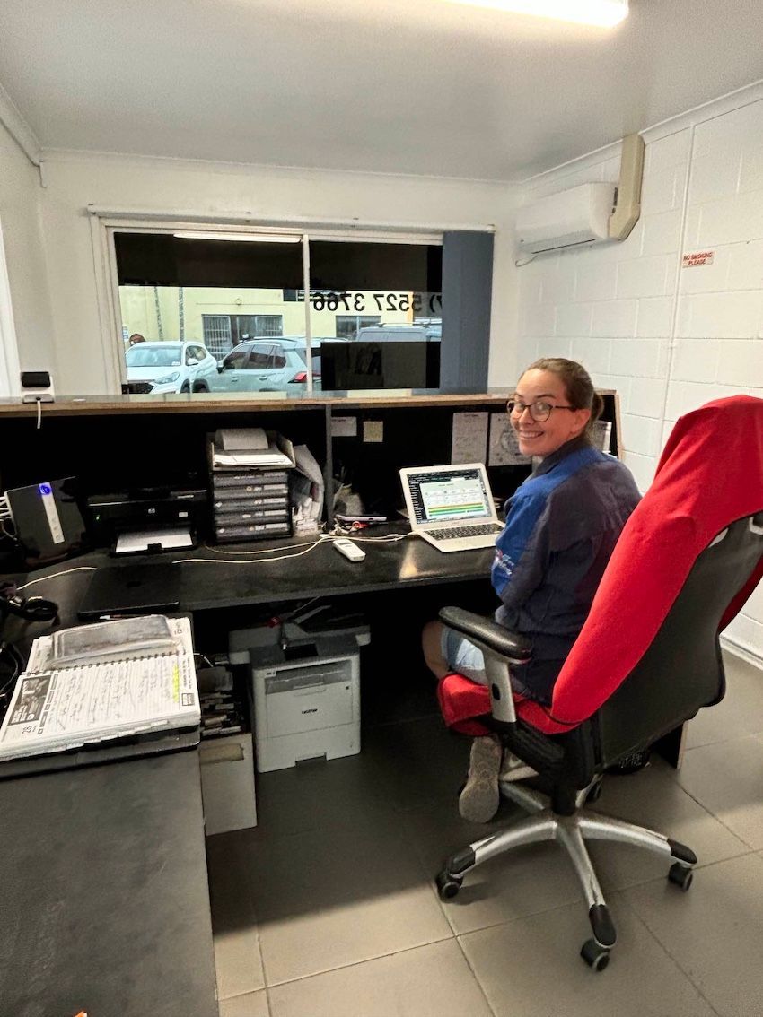 A woman is sitting at a desk in an office with a laptop. — Sure Stop Automotive Centre In Nerang, QLD