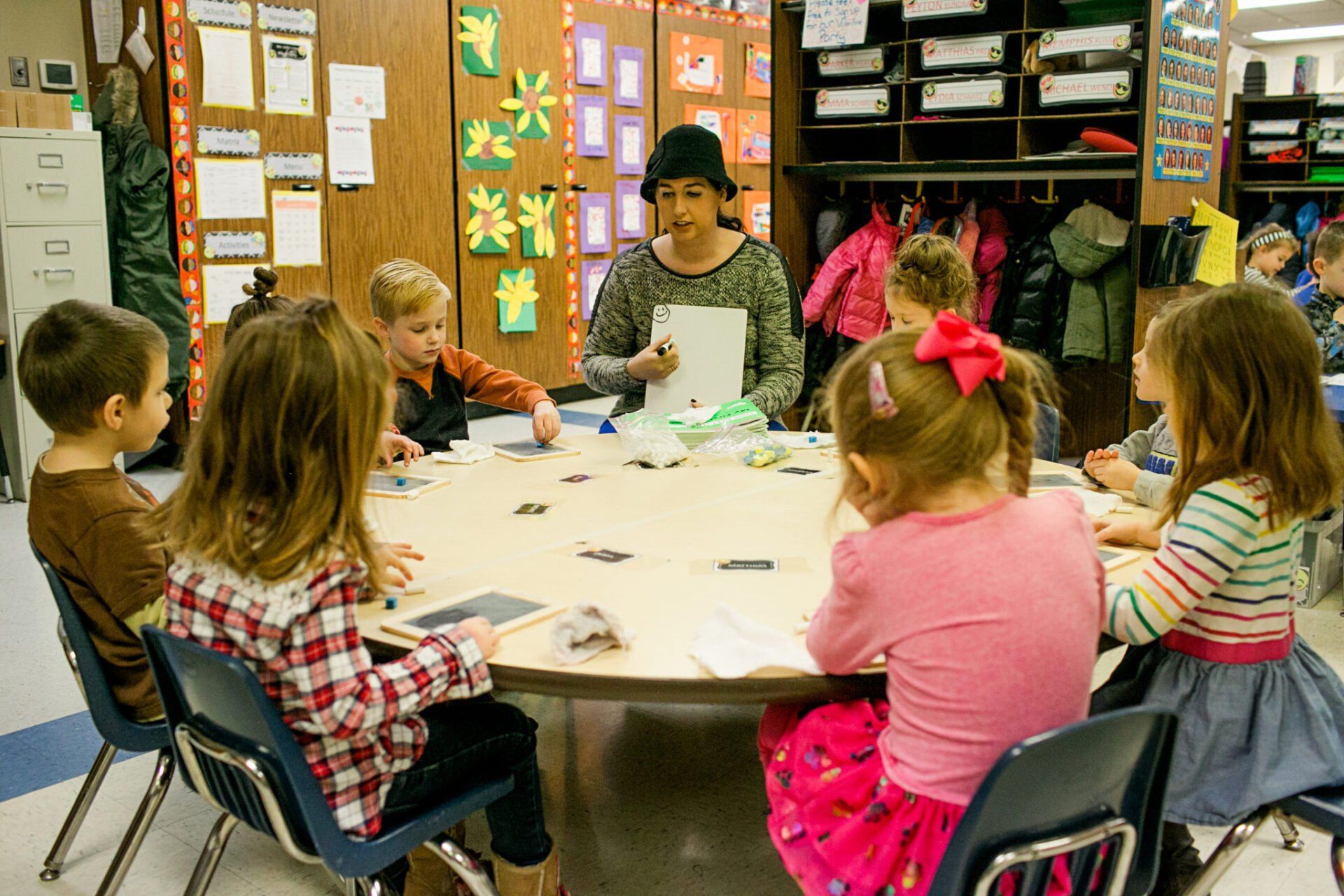 A group of children are sitting around a table in a classroom