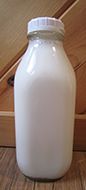 White plastic milk bottle with white cap on a wooden surface.