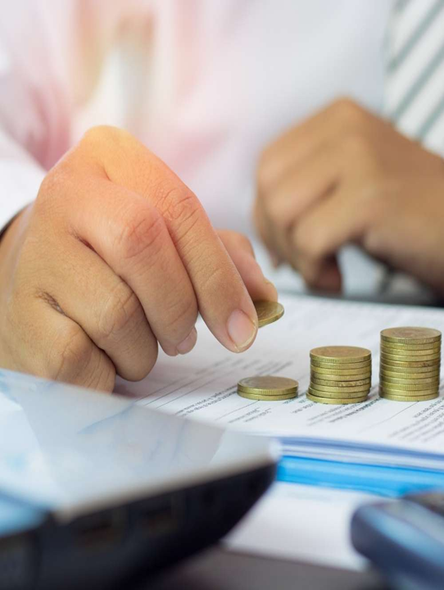 Person stacking coins on a document, suggesting savings or financial planning.