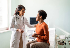 Doctor in white coat comforts patient seated on examination table.