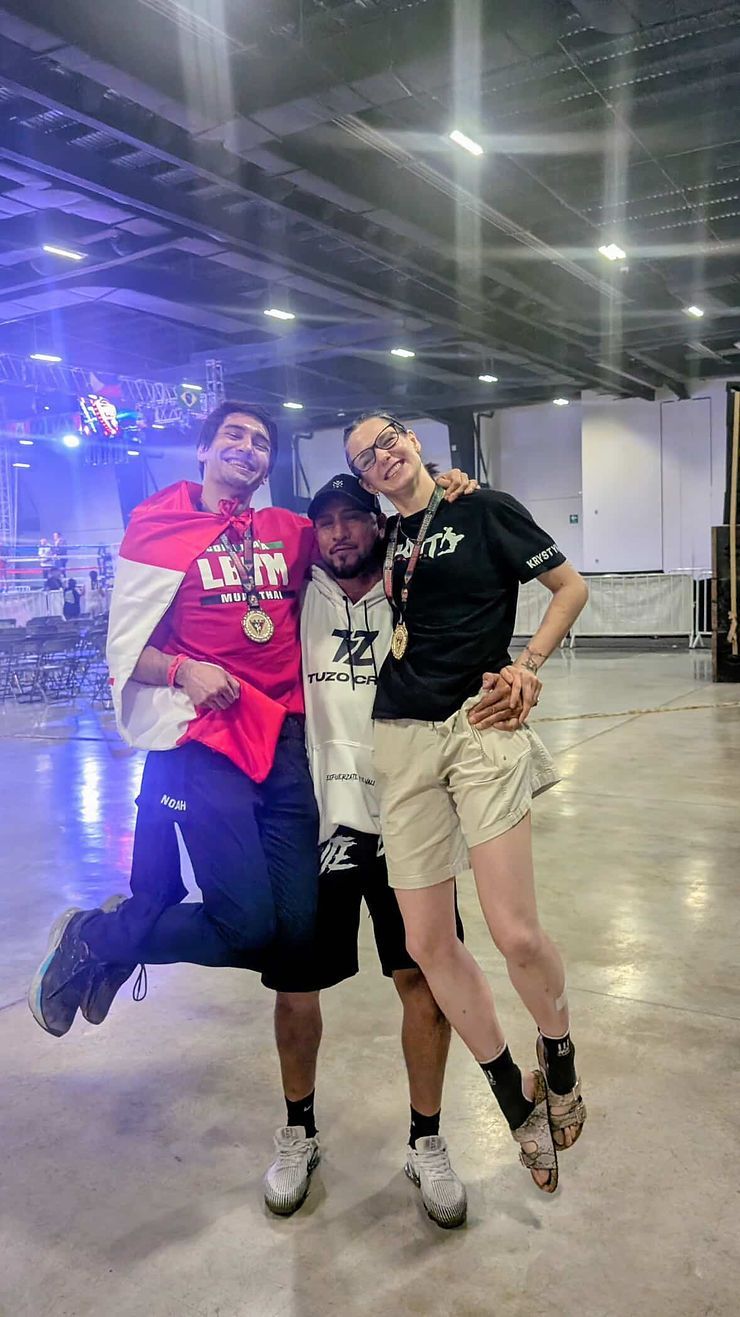Kingdom Muay Thai in Richmond Ontario Three people posing together in a brightly lit indoor venue, smiling and standing close.