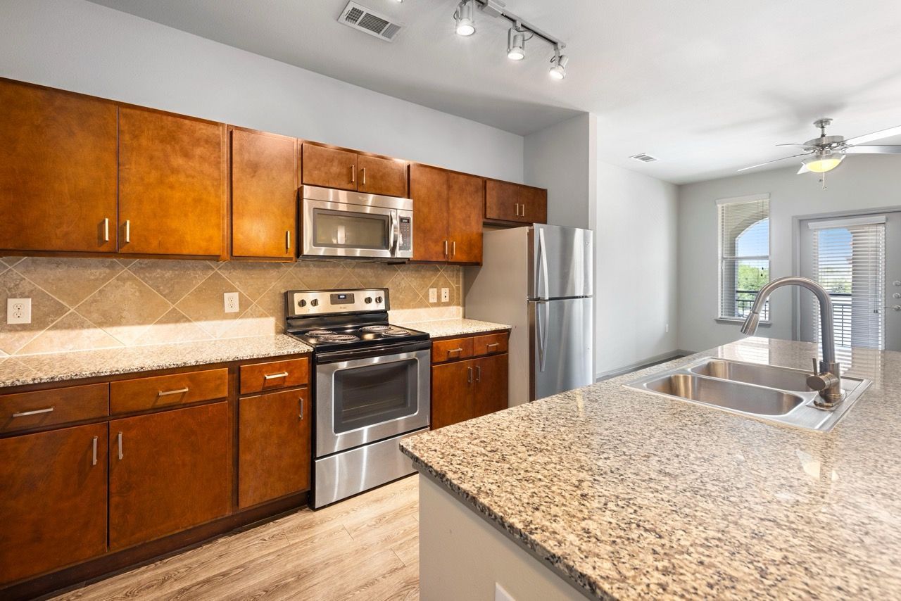 Kitchen with granite countertops, wooden cabinets, stainless appliances, and a double-basin sink.