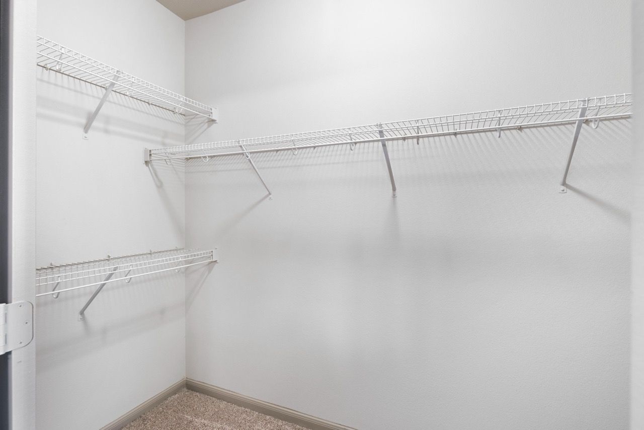 Empty walk-in closet with white wire shelving along the walls.
