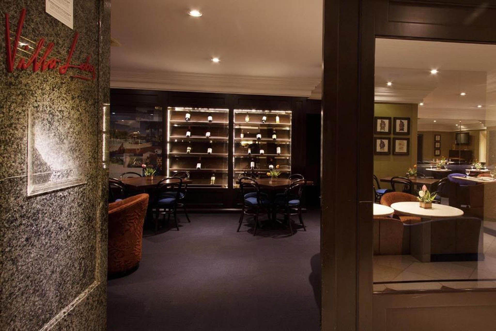 Interior de restaurante sofisticado com adega, iluminação suave e mesas postas para refeições.