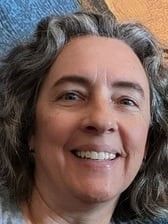 A woman with gray hair is smiling for the camera. A woman with gray hair is smiling for the camera.