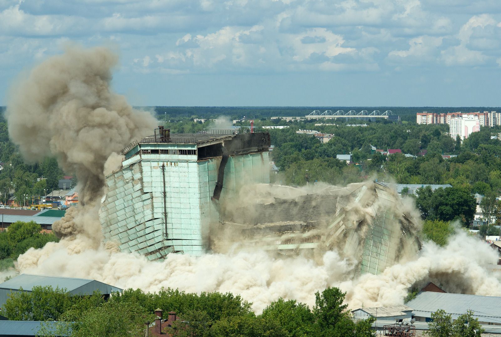 A large building is being demolished with a lot of smoke coming out of it.