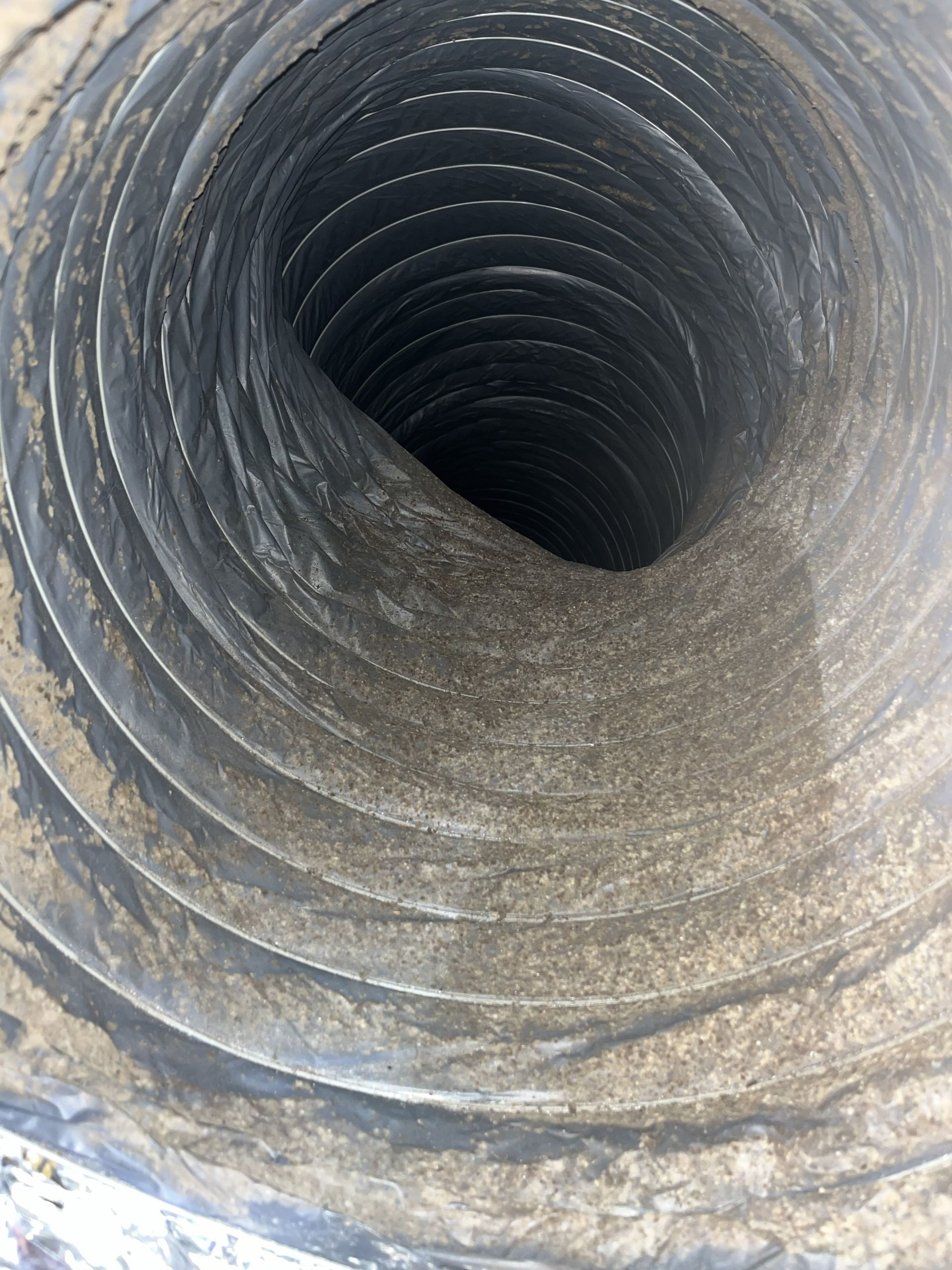 Inside view of a large corrugated metal pipe or tunnel, dark and cylindrical with textured walls.