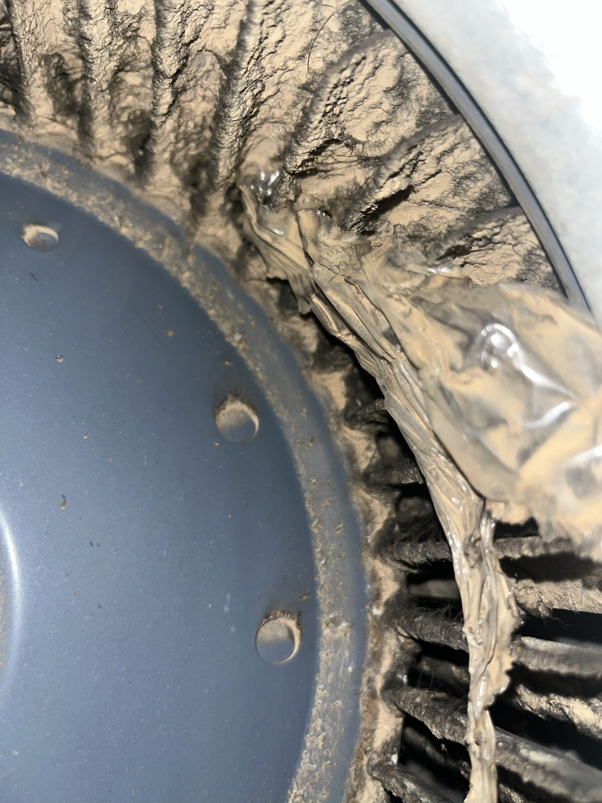 Close-up of a dirty tire rim with mud and debris packed in the tread and wheel well