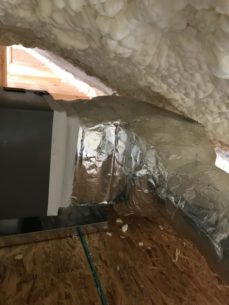 Attic insulation with foam ceiling, foil-lined wall, and wood floor panels near ductwork