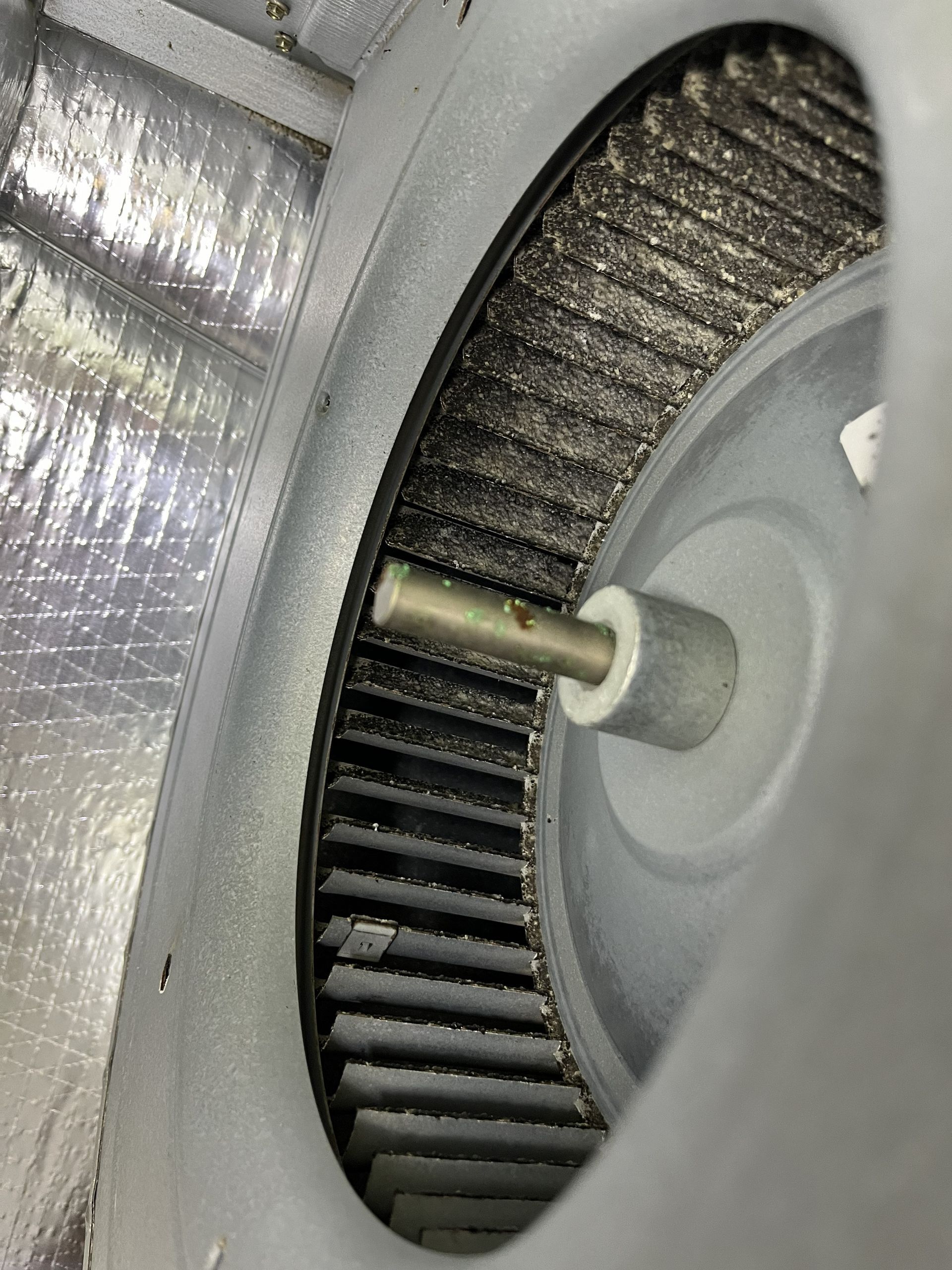 Close-up of a metal wheel or fan rotor with spokes inside a gray housing.
