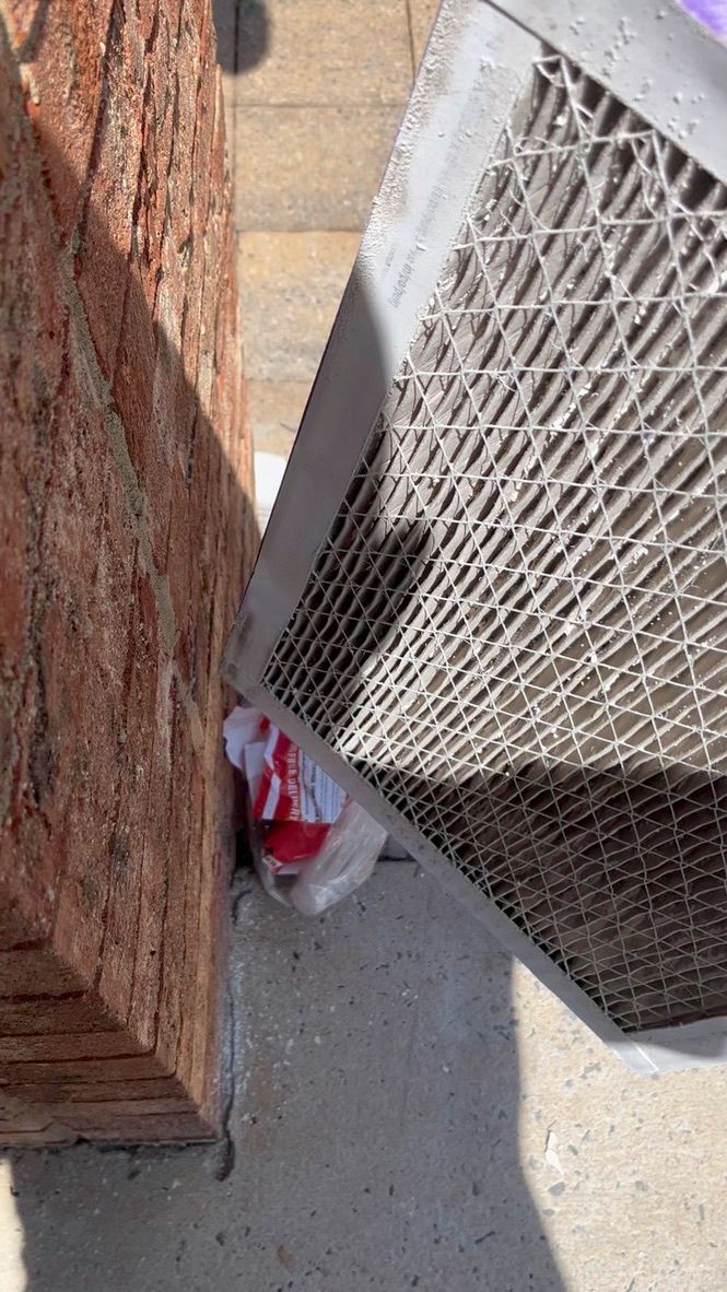 Red brick wall and metal fence beside a narrow concrete walkway with a red-and-white object on the ground.