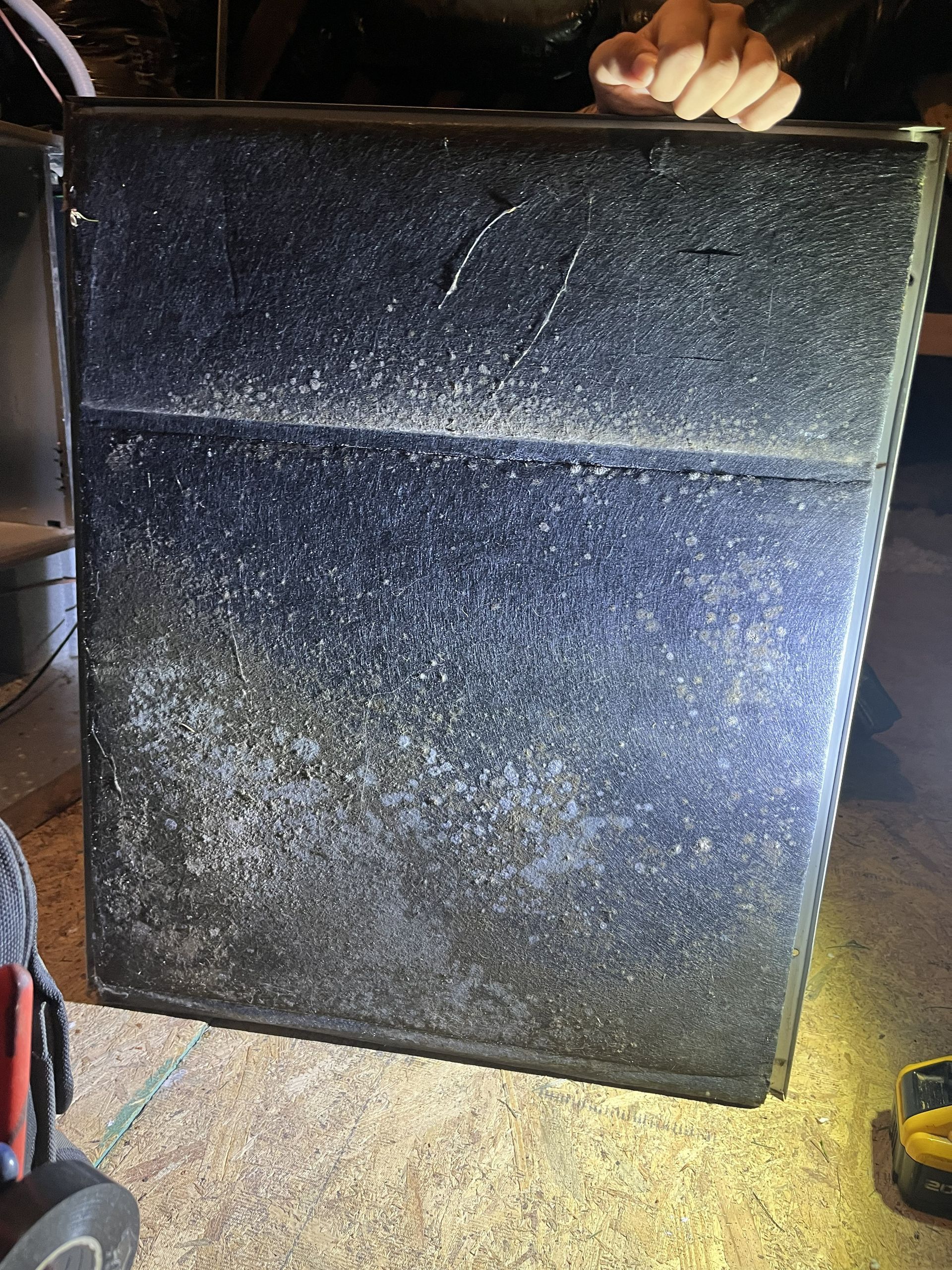 Large black textured speaker cabinet with a hand resting on top in a dim indoor setting