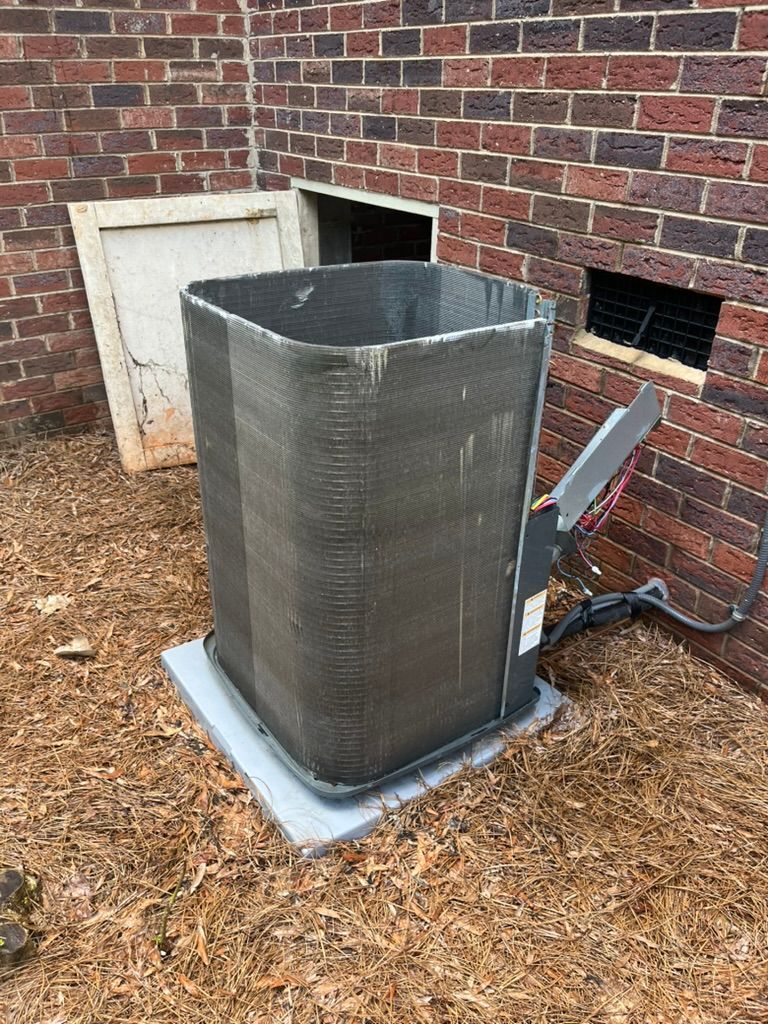 Outdoor HVAC unit beside a brick building on a concrete pad, with a service panel and connected wiring